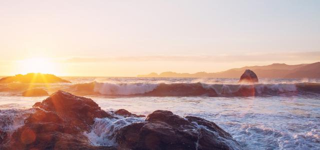 Sea foam on rocks at sunset